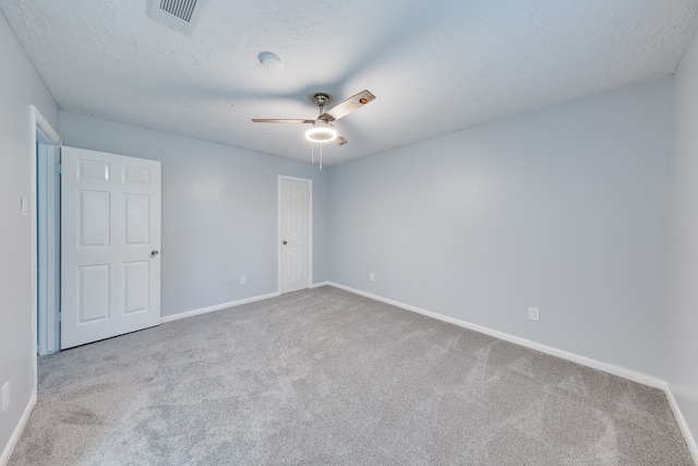 carpeted empty room featuring ceiling fan and a textured ceiling