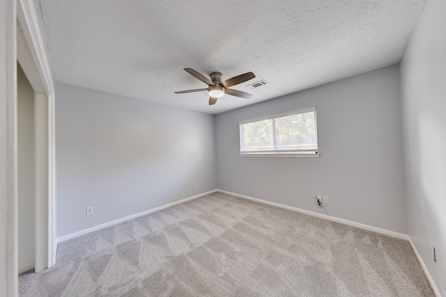 spare room featuring light carpet, a textured ceiling, and ceiling fan