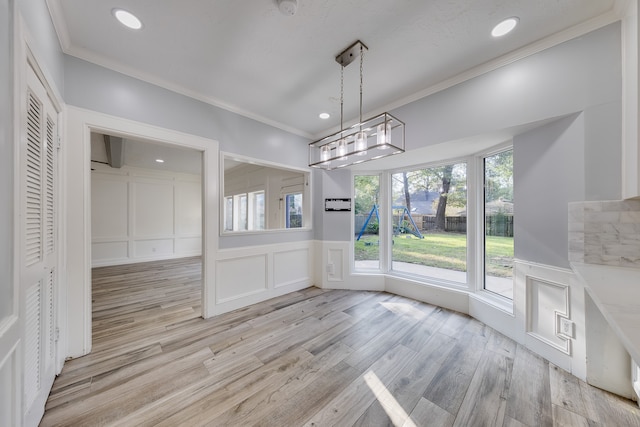 unfurnished dining area with a chandelier, light hardwood / wood-style flooring, and ornamental molding