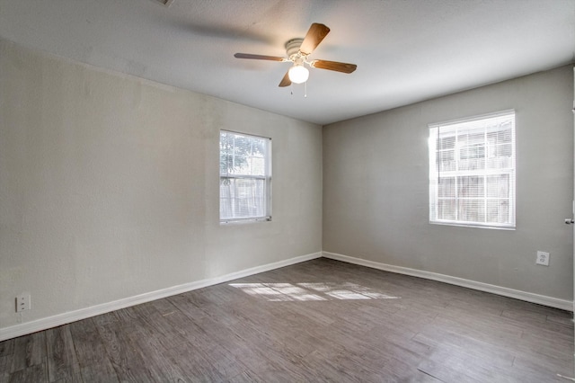 empty room with dark hardwood / wood-style flooring, plenty of natural light, and ceiling fan