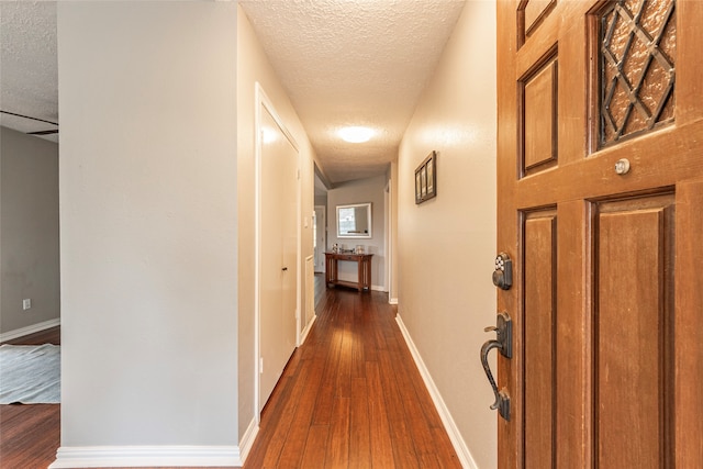 corridor with a textured ceiling and dark hardwood / wood-style floors