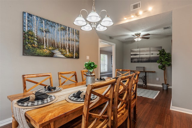 dining space with a textured ceiling, dark wood-type flooring, and ceiling fan with notable chandelier