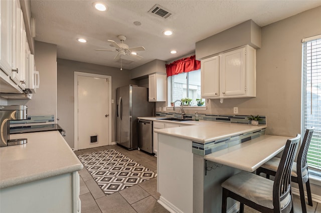 kitchen with ceiling fan, sink, kitchen peninsula, white cabinets, and appliances with stainless steel finishes