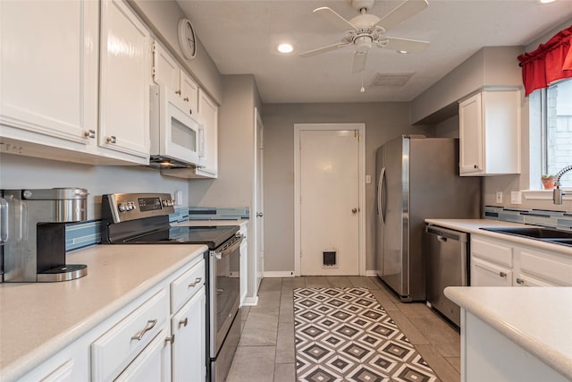 kitchen with stainless steel appliances, ceiling fan, sink, light tile patterned floors, and white cabinets