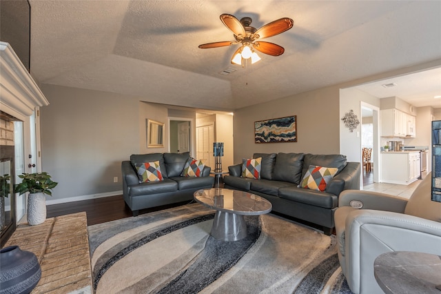 living room featuring hardwood / wood-style flooring, ceiling fan, and a textured ceiling