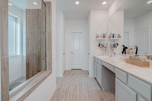 bathroom featuring vanity, a tile shower, and wood-type flooring