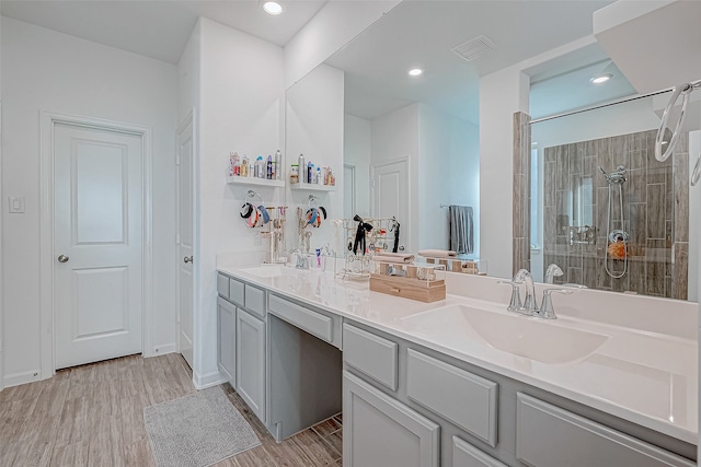 bathroom featuring vanity, wood-type flooring, and tiled shower