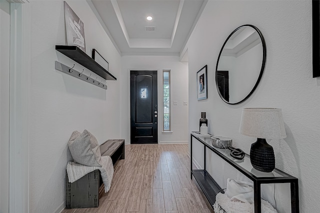 entryway with a raised ceiling and light wood-type flooring