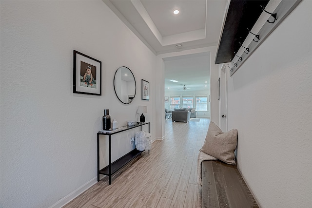 hallway featuring a raised ceiling and light wood-type flooring