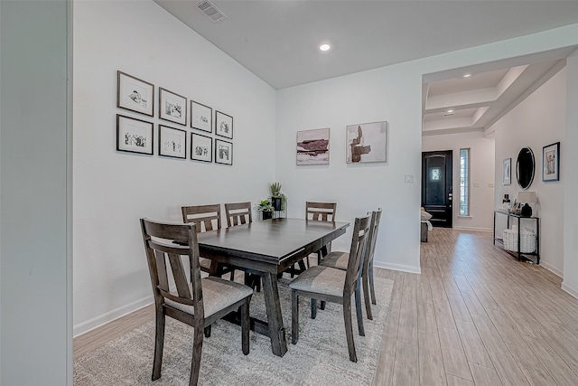 dining space with a raised ceiling and light hardwood / wood-style flooring