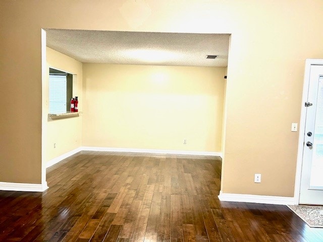 empty room with dark hardwood / wood-style flooring and a textured ceiling