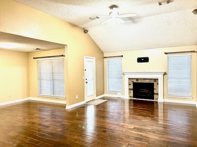 unfurnished living room with ceiling fan, dark hardwood / wood-style floors, lofted ceiling, a textured ceiling, and a fireplace