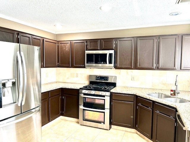 kitchen with dark brown cabinetry, sink, stainless steel appliances, light stone counters, and light tile patterned floors