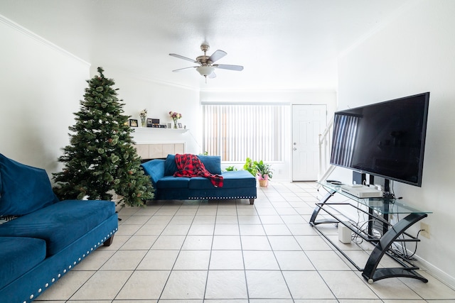 tiled living room with a tile fireplace, ceiling fan, and ornamental molding