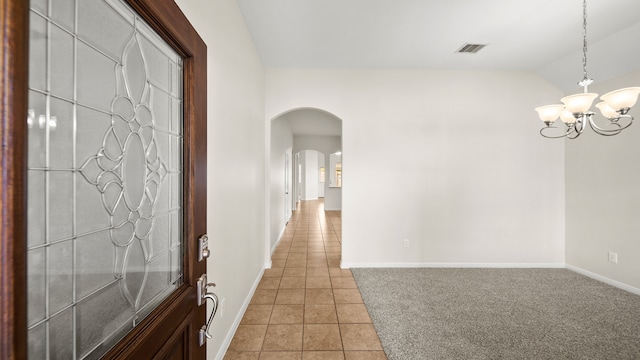 tiled entryway featuring vaulted ceiling and a notable chandelier