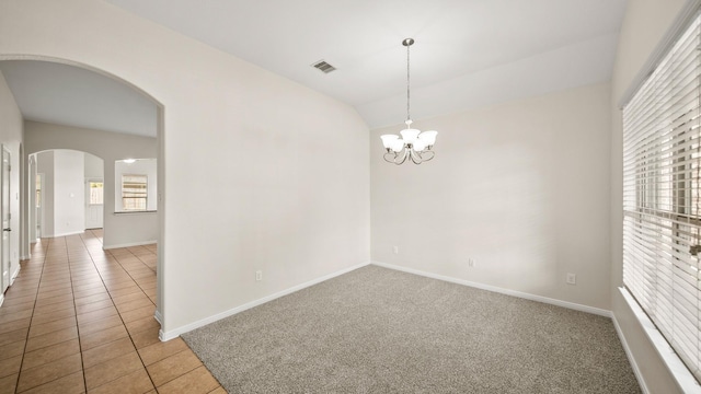 tiled empty room featuring lofted ceiling and a notable chandelier