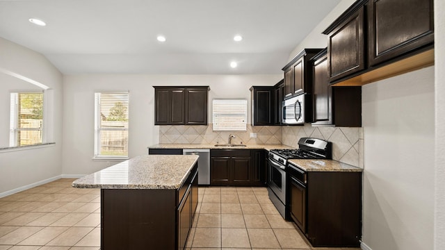 kitchen featuring tasteful backsplash, stainless steel appliances, sink, light tile patterned floors, and a kitchen island