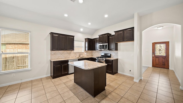 kitchen featuring a center island, sink, stainless steel appliances, vaulted ceiling, and decorative backsplash