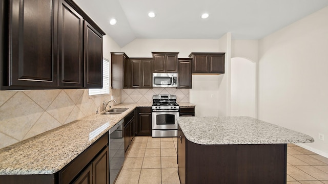 kitchen with sink, a center island, light tile patterned flooring, and appliances with stainless steel finishes