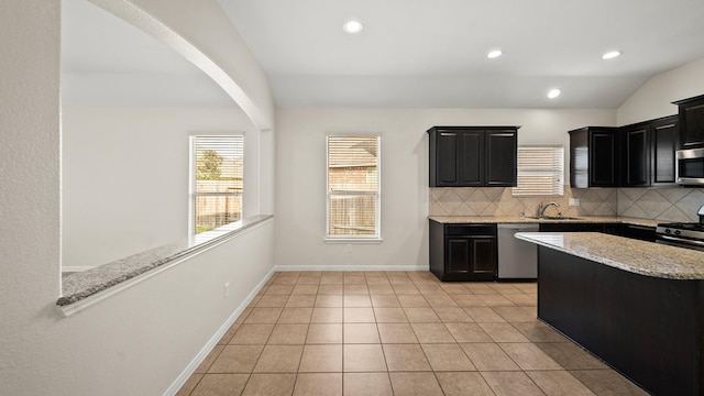 kitchen with lofted ceiling, decorative backsplash, light stone countertops, light tile patterned floors, and stainless steel appliances