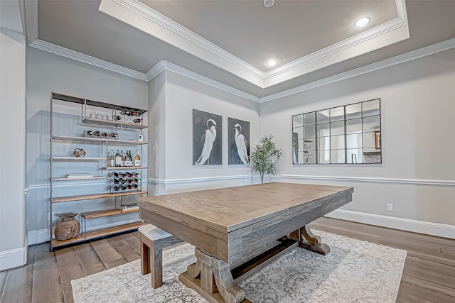 home office with a raised ceiling, ornamental molding, and hardwood / wood-style flooring