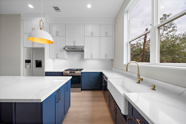 kitchen with light stone countertops, white cabinetry, hanging light fixtures, and appliances with stainless steel finishes