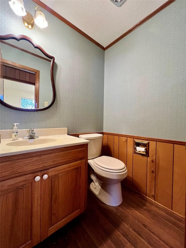 bathroom with ornamental molding, vanity, a textured ceiling, hardwood / wood-style floors, and toilet