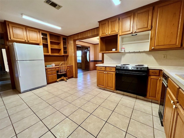 kitchen with black range with electric stovetop, white fridge, wooden walls, light tile patterned floors, and built in desk