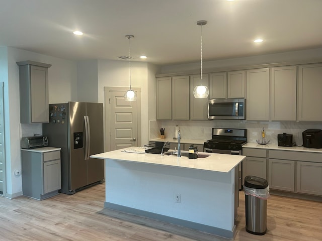 kitchen with hanging light fixtures, light hardwood / wood-style flooring, stainless steel appliances, and sink