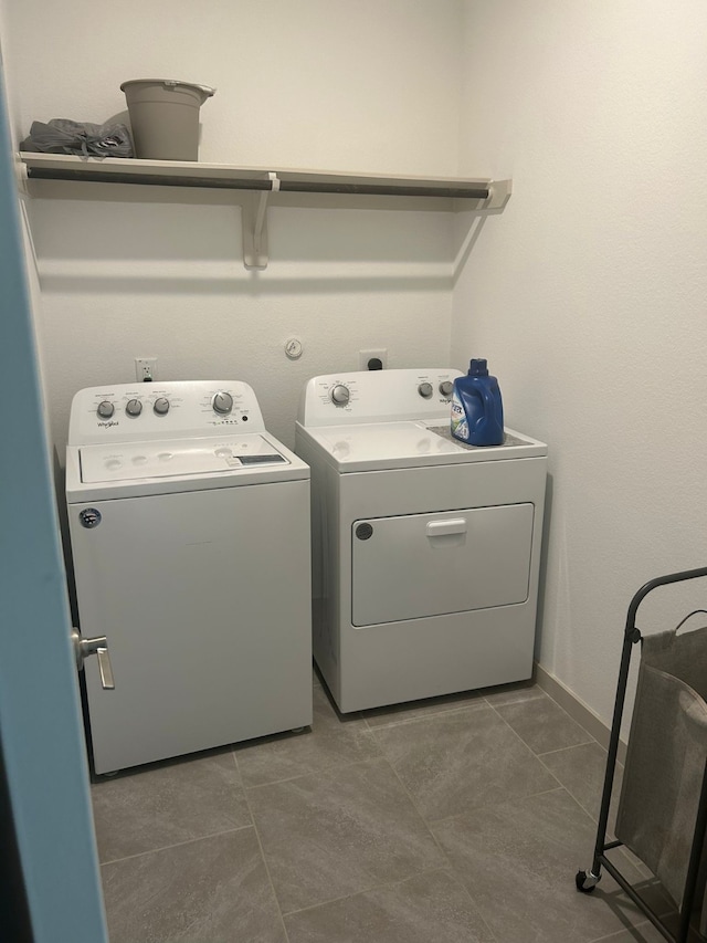 clothes washing area with dark tile patterned flooring and washer and dryer