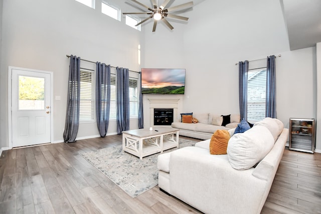 living room featuring ceiling fan, a high ceiling, and hardwood / wood-style flooring