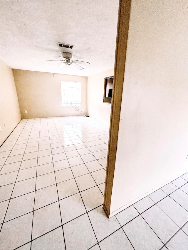 spare room with ceiling fan, light tile patterned floors, and a textured ceiling