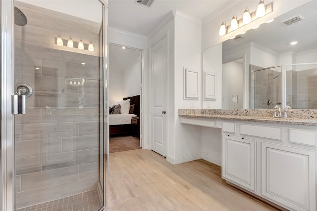 bathroom with crown molding, hardwood / wood-style floors, vanity, and a shower with shower door