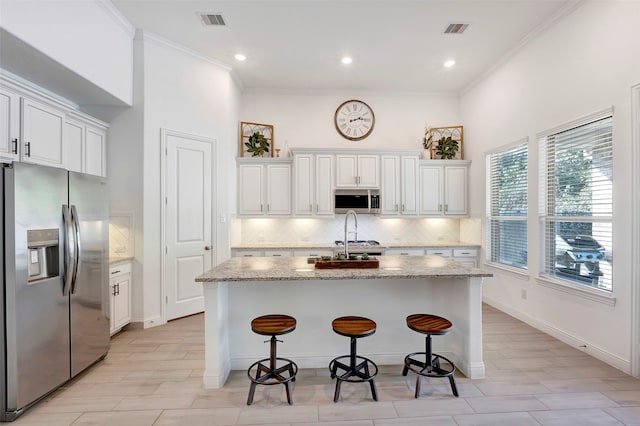 kitchen with white cabinetry, stainless steel appliances, and an island with sink