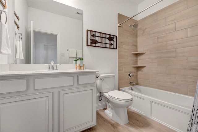 full bathroom featuring hardwood / wood-style flooring, vanity, toilet, and tiled shower / bath