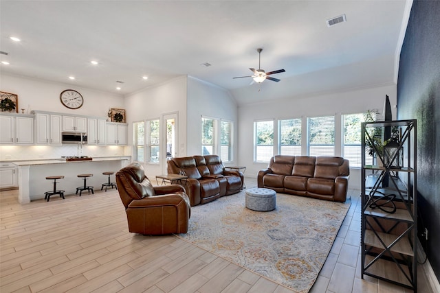 living room featuring vaulted ceiling, light hardwood / wood-style flooring, ceiling fan, and crown molding