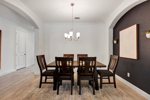 dining space with a notable chandelier, crown molding, and light hardwood / wood-style flooring