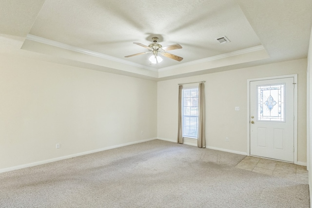 foyer entrance featuring a tray ceiling, crown molding, plenty of natural light, and light colored carpet