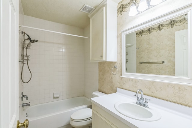 full bathroom featuring vanity, tiled shower / bath, a textured ceiling, and toilet