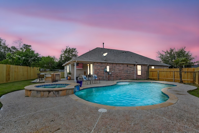 pool at dusk with an in ground hot tub and a patio