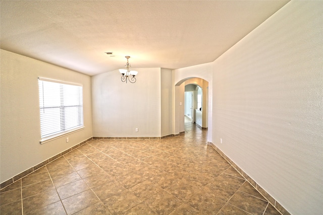 unfurnished room with a notable chandelier and a textured ceiling