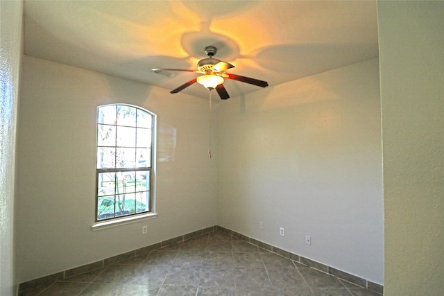 empty room with dark tile patterned flooring and ceiling fan