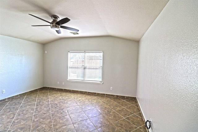 unfurnished room with dark tile patterned flooring, a textured ceiling, vaulted ceiling, and ceiling fan