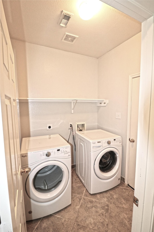 clothes washing area featuring dark tile patterned floors, a textured ceiling, and washing machine and clothes dryer