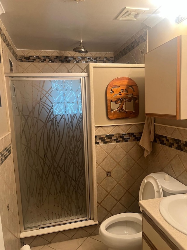 bathroom featuring vanity, a shower with door, tile walls, tile patterned flooring, and toilet