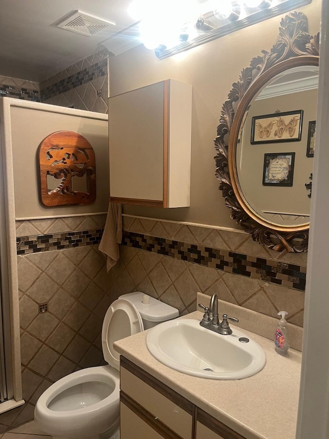 bathroom featuring vanity, toilet, and tile walls