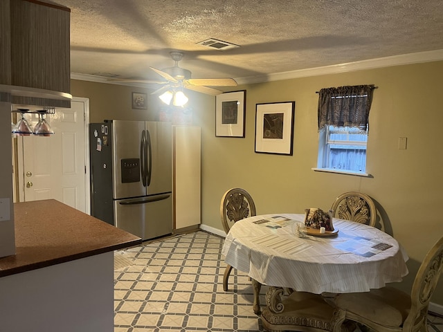 dining room featuring ceiling fan, a textured ceiling, and ornamental molding