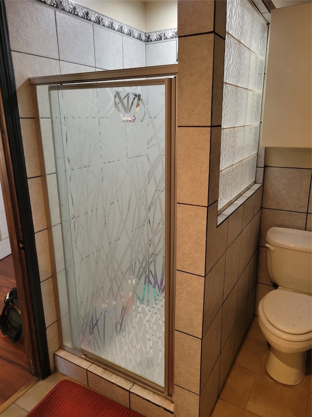 bathroom featuring tile patterned flooring, toilet, and tile walls