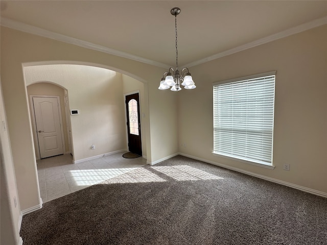 carpeted spare room with a healthy amount of sunlight, crown molding, and a chandelier