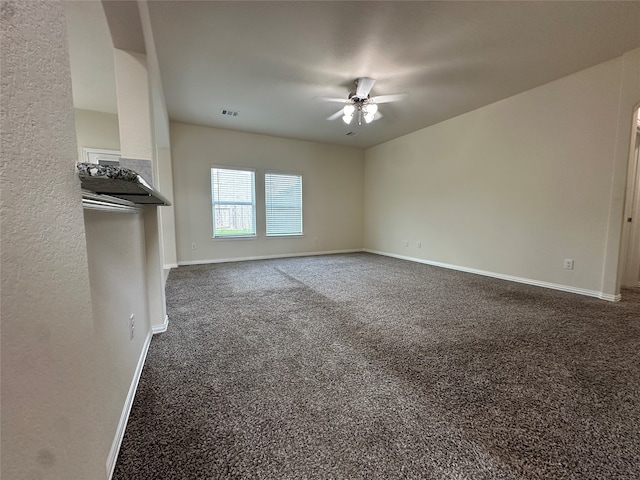 unfurnished living room with ceiling fan and dark carpet